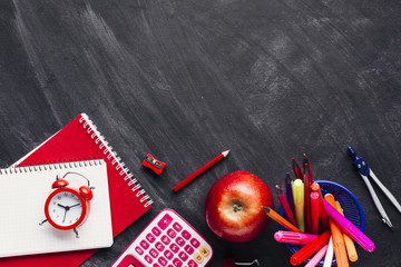 Bright red school supplies and apple on chalkboard