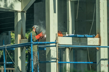 Welding work. A worker in overalls and a protective mask welds the flange to the pipe in the street. Repair work in the construction industry.