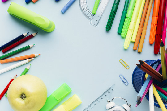 Colorful school stationery scattered around empty space on blue desk