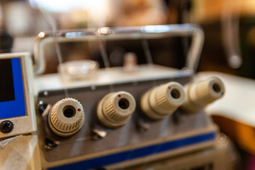 Overlock knobs in a sewing workshop. A closeup view of the spool control dials on a vintage overlock machine. Old-fashioned retro machinery of a seamstress inside atelier.