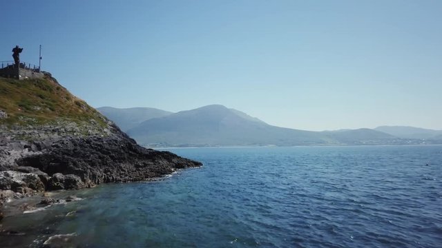 fast dolly in drone shot passing by St. Brendan The Navigator statue, Fenit, County Kerry, Ireland