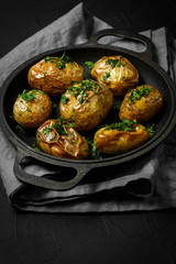 baked potatoes on pan with seasonal greens parsley, dill, green onions