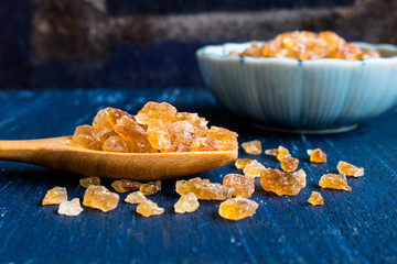 Natural rock sugar in wooden spoon on rustic table