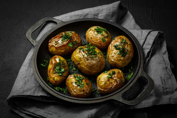 baked potatoes on pan with seasonal greens parsley, dill, green onions
