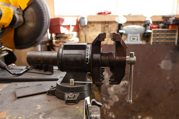 Bench vise attached to a worktop. A closeup and side profile view of a cast iron metalworking bench vise inside a workshop, used to hold pieces of metal stable whilst work is carried out.