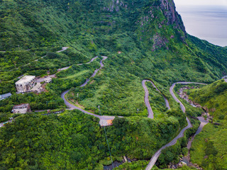 Aerial view of cars driving on curved, zigzag road or street on mountain hill with green natural...