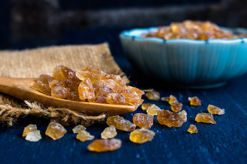Natural rock sugar in wooden spoon on rustic table
