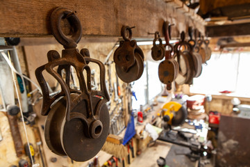 Rusty lifting wheels hanging in workshop. A closeup view on old rusted pulleys hung from a wooden...