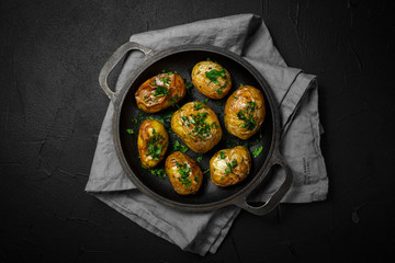 baked potatoes on pan with seasonal greens parsley, dill, green onions