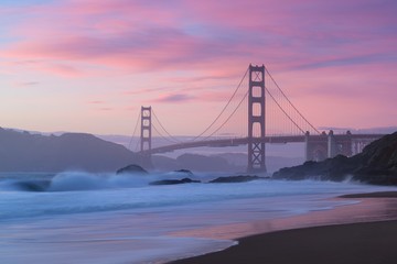 Classic panoramic view of famous Golden Gate Bridge seen from scenic Baker Beach in beautiful golden evening light on a dusk with blue sky and clouds in summer, San Francisco, California, USA