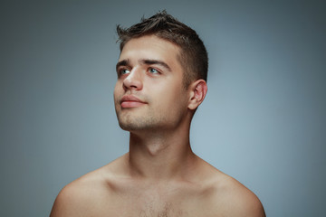 Portrait of shirtless young man isolated on grey studio background. Caucasian healthy male model...