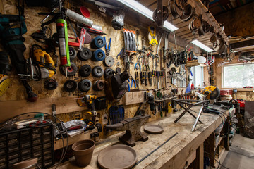 Tools hanging above bench in workshop. A variety of metalwork tools including abrasive cutting discs hang over a workbench inside a garage. Handy tools neatly organized above a workstation.