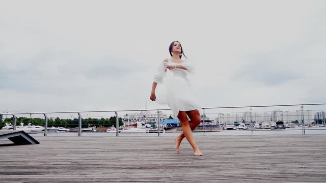 the waterfront girl in a white dress dancing