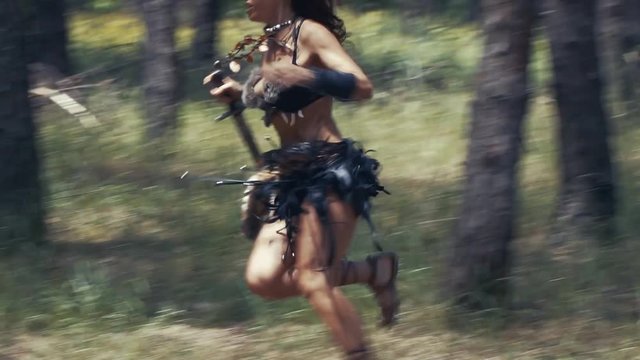 Scary big barbarian man is chasing an amazon woman in the forest