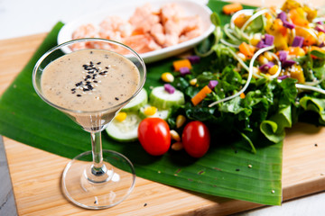 Fresh salad plate with shrimp, salmon, tomato and mixed greens  on wooden background .