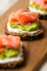 open sandwich with avocado and salmon on wood board