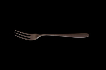 cake fork on black background. Close-up of stainless fork with copy space.