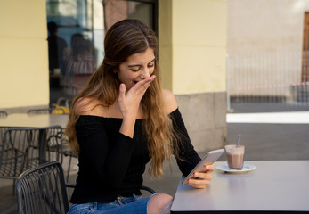 Obraz premium Attractive young woman sitting bored in a coffee shop using smart mobile phone feeling disappointed