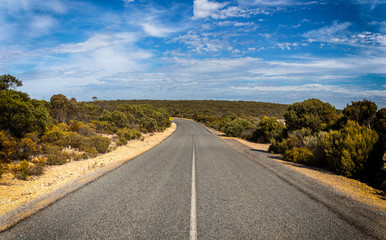 Naklejka premium Australian outback road on a sunny day with blue sky