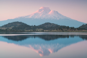A reflection of snow capped Mount Shasta in a clear water in lake  at sunrise in California State,...