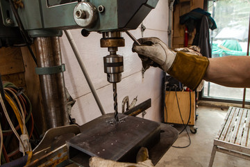 Blacksmith uses drill press in garage. A close up view of a metalworker operating a bench drill...