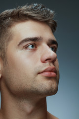 Naklejka premium Portrait of shirtless young man isolated on grey studio background. Caucasian healthy male model looking at side and posing. Concept of men's health and beauty, self-care, body and skin care.