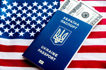 Ukrainian biometric passport on the background of the American flag with banknotes of one hundred dollars.