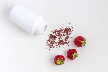 Vitamins supplements as a capsule with berries from medicine jar on white background.
