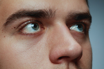 Close-up portrait of young man isolated on grey studio background. Caucasian male model's face and...