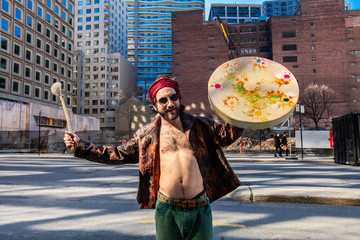 Sacred man holding native drum downtown. A confident shaman is seen standing topless on a city...