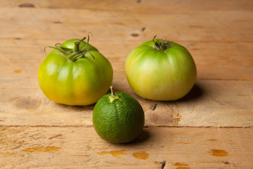 Productos verdes del campo, la hierba de la menta, el tomate verde y la naranja verde sobre una madera rústica.