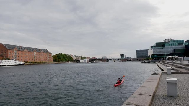 Young woman kayaking though river in Copenhagen city centre in Denmark