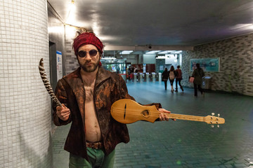 Shaman holds guitar in underground. A sacred man stands in an underground tunnel with merlin guitar...
