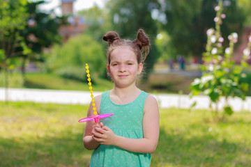 Little beautiful girl sitting on the green grass in the park, soft focus background