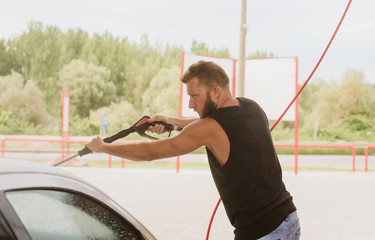 Cleaning car using high pressure water. Man washing his car under high pressure water in service