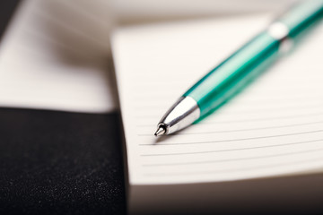 Opened notepad with automatic plastic ballpoint pen close up. Toned vintage