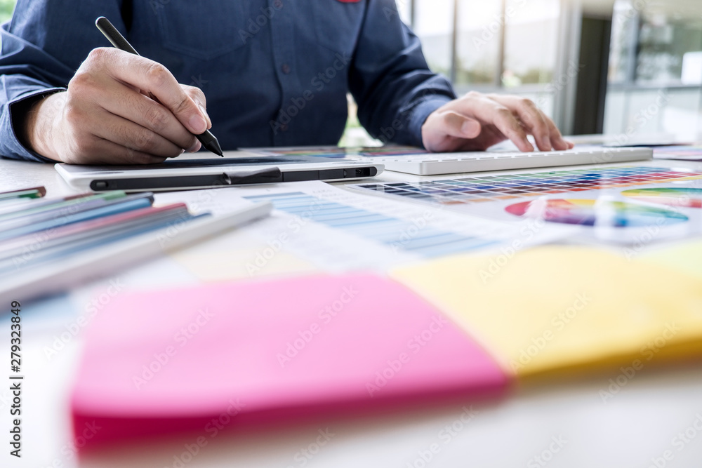 Poster male creative graphic designer working on color selection and color swatches, drawing on graphics ta