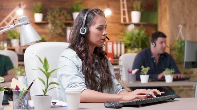 Customer support operators are working in cozy office. Beautiful woman talks using the headsets