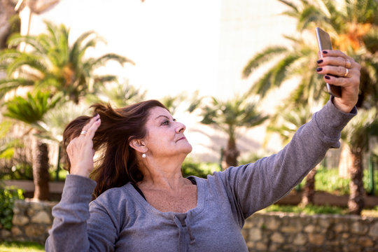 Donna matura in tuta si fa un selfie con il suo cellulare al parco