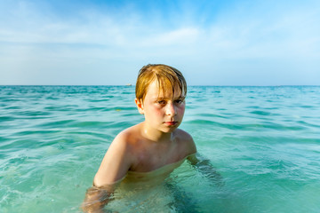 Fototapeta na wymiar angry young boy is walking thru the clear warm saltwater