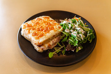 Freshly served food in restaurant. A close up shot of a tasty lunch served in a bistro, consisting of croque monsieur - a toasted sandwich filled with cheese and ham, and a serving of fresh salad