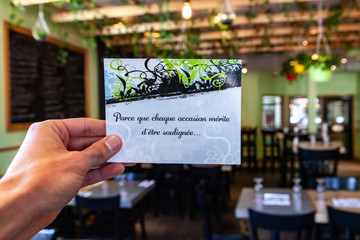 Printed leaflet in trendy bistro. A closeup view of a French card held inside a modern restaurant,...