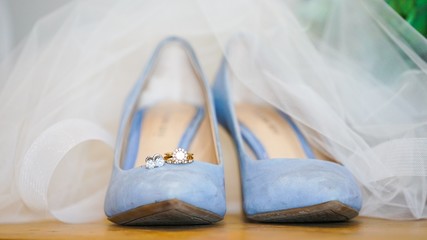 Closeup of beautiful light blue female wedding shoes under a white wedding dress