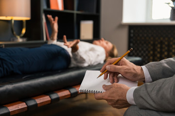 Male psychotherapists hands making notes in his notepad