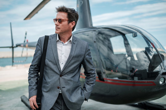 Businessman talking on cellphone near private helicopter