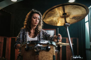 Fototapeta na wymiar Woman playing drums during music band rehearsal