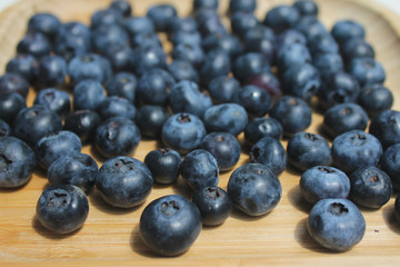 Ripe juicy blueberry on wooden plate. Food summer background