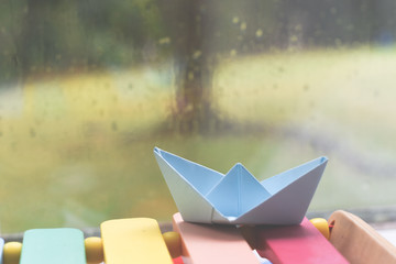 Origami boat by a window on a rainy day inside the house