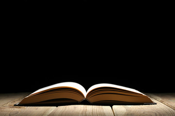 open book on a wooden table and black background  with copy space for your text