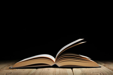 open book on a wooden table and black background  with copy space for your text